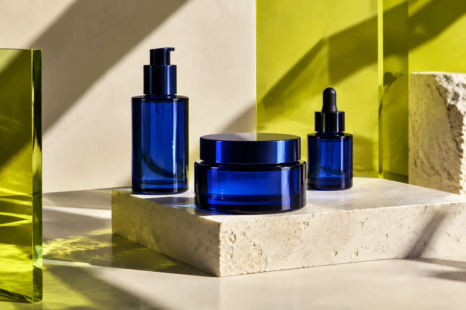 Three blue glass containers on a studio set with lime-yellow panels